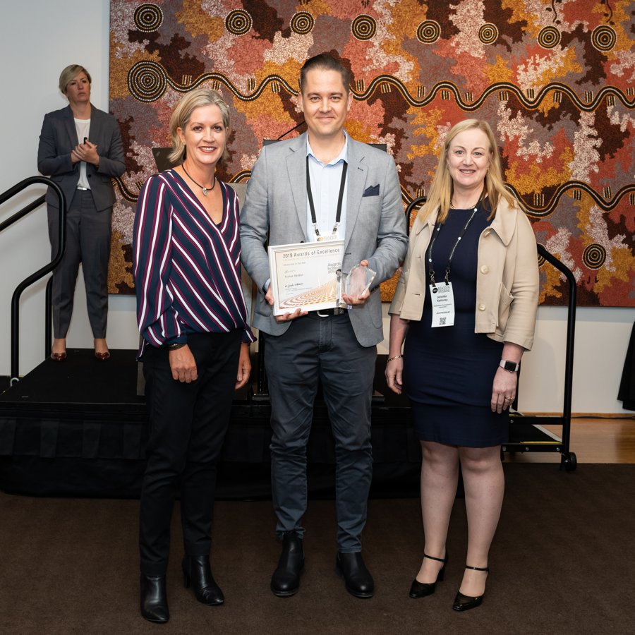 Tristan holding the 2019 Researcher of the Year certificate and trophy with two colleagues at the ASA conference in Brisbane.